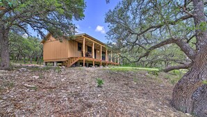 A wooden cabin with a porch, surrounded by trees and a rocky ground. - Rustic-chic Country Cabin - 10 Mi to Main Street! (Fredericksburg)