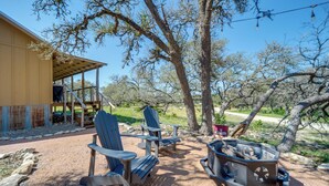An outdoor seating area with Adirondack chairs, a fire pit, and a covered patio. - Rustic-chic Country Cabin - 10 Mi to Main Street! (Fredericksburg)