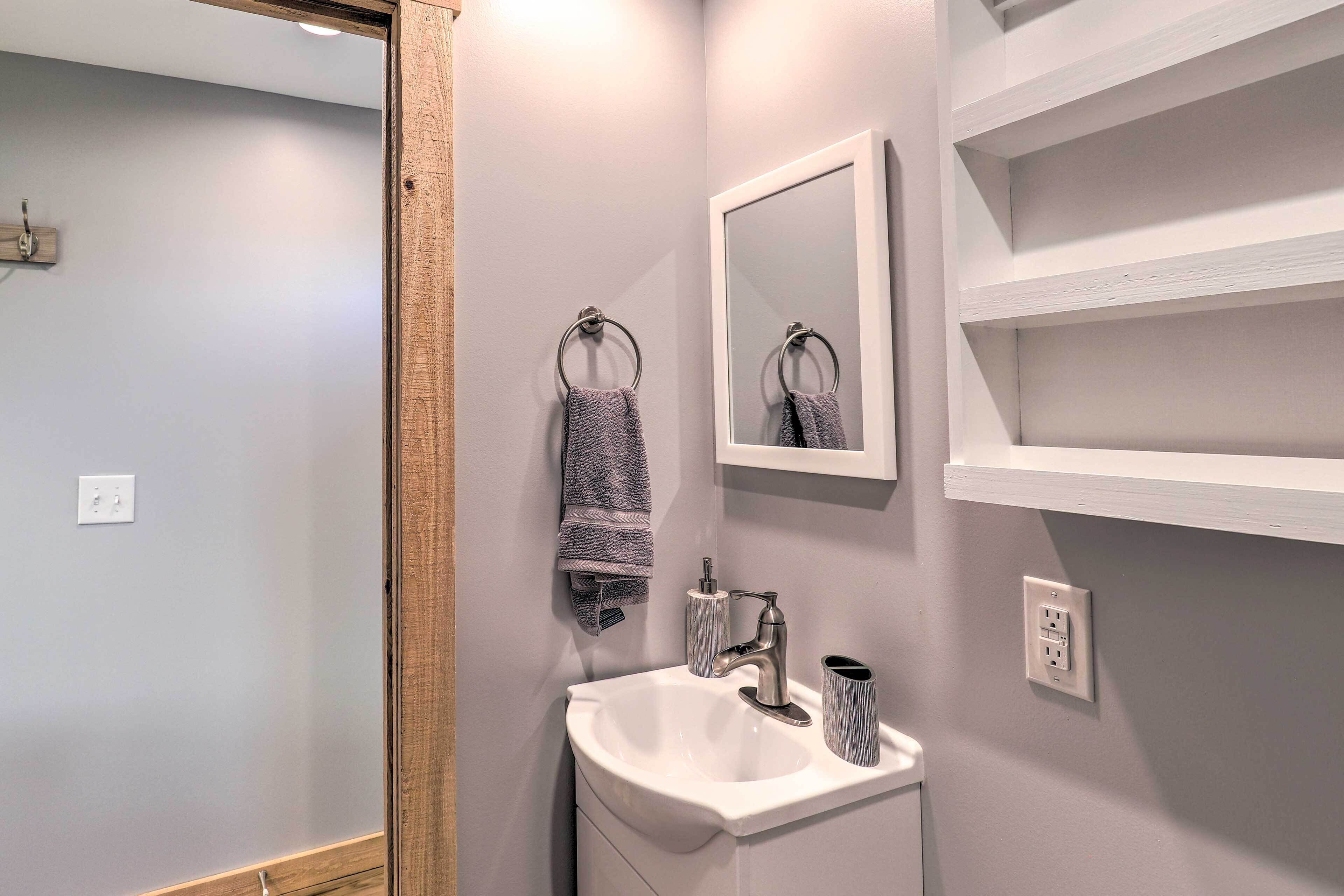 A bathroom with a white sink, a mirror, and a towel rack.