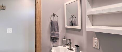 A bathroom with a white sink, a mirror, and a towel rack.
