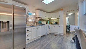 A modern kitchen with white cabinets, stainless steel appliances, and a skylight.