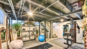 Une salle de sport à domicile équipée de matériel d’exercice, d’un ballon d’exercice bleu, d’un pouf et d’un miroir.