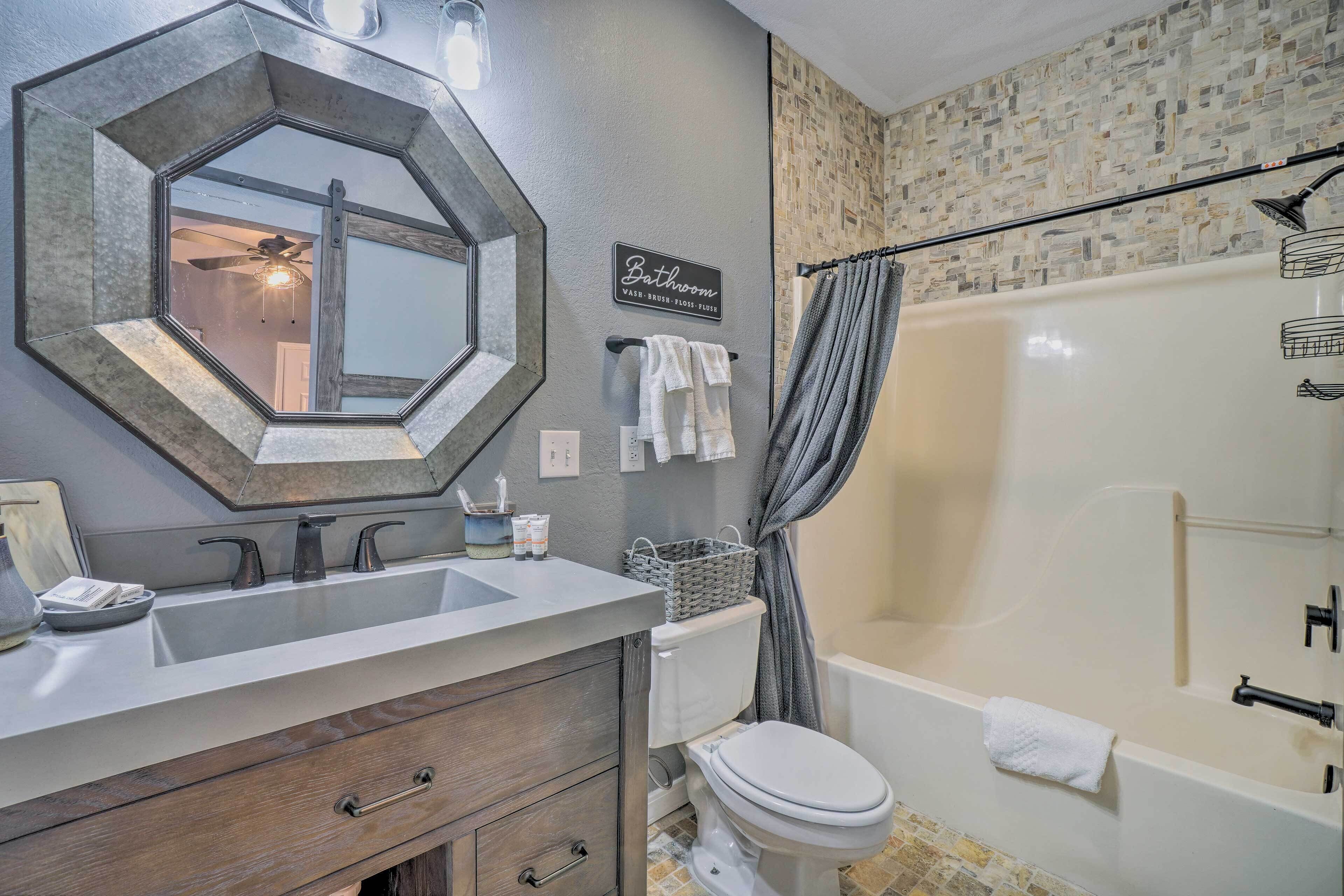 A bathroom with a large mirror, a sink, a toilet, and a bathtub.