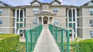 A multi-story residential building with a central entrance, green railings, and a symmetrical facade.
