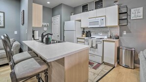 A compact kitchen with white appliances, a central island, and a dining area with chairs.