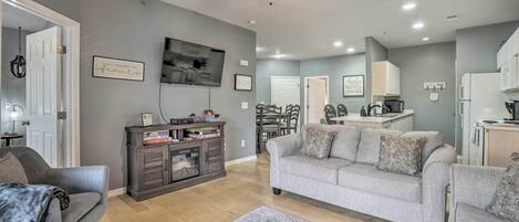 A modern living room with a grey sofa, a coffee table, and a TV mounted on the wall.