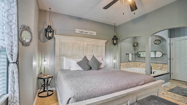 A bedroom with a bed, bedside table, lamp, and a ceiling fan.