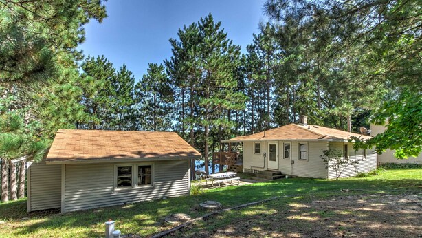 Two cabins with sloped roofs, surrounded by dense pine trees. - Lakefront Studio Cabin w/ Dock & Fire Pit! (Westfield)
