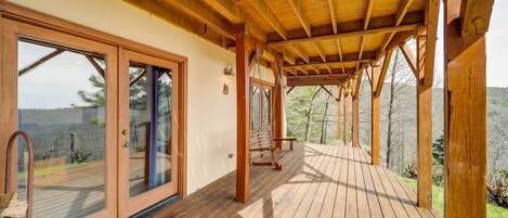 A wooden deck with glass doors leading to a covered area.