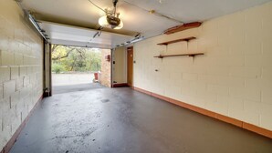 A clean, empty hallway with a concrete floor, white brick walls, and a door leading outside. - Cute Home w/ Patio ~ 7 Mi to Dtwn Pittsburgh (Pittsburgh)
