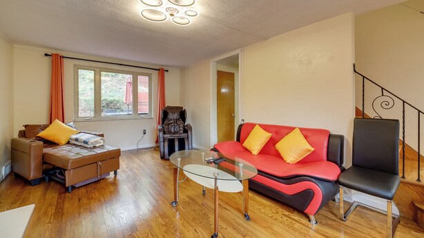A modern living room with a glass coffee table, a red sofa, a brown sofa, and a black chair. - Cute Home w/ Patio ~ 7 Mi to Dtwn Pittsburgh (Pittsburgh)