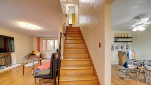 A staircase leading to a second floor, a dining area with a glass table, and a kitchen area with shelves. - Cute Home w/ Patio ~ 7 Mi to Dtwn Pittsburgh (Pittsburgh)