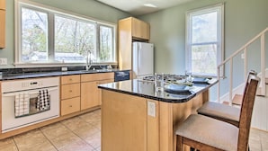 A modern kitchen with a central island, wooden cabinets, and a built-in dishwasher. - Family-friendly Cambridge Home w/ Fire Pit! (Cambridge)