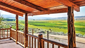 A wooden deck with a view of a green valley and distant mountains. - Remote Antimony Log Cabin w/ Green Meadow Views! (Antimony)