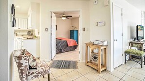 A room with a bed, a desk, a chair, a small table, and a door leading to another room. - Mountain-view Albuquerque Townhome w/ Patio! (Albuquerque)