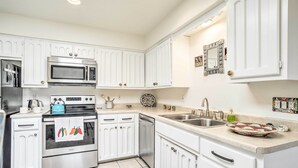 A kitchen with white cabinetry, a stainless steel oven, a microwave, and a sink. - Mountain-view Albuquerque Townhome w/ Patio! (Albuquerque)