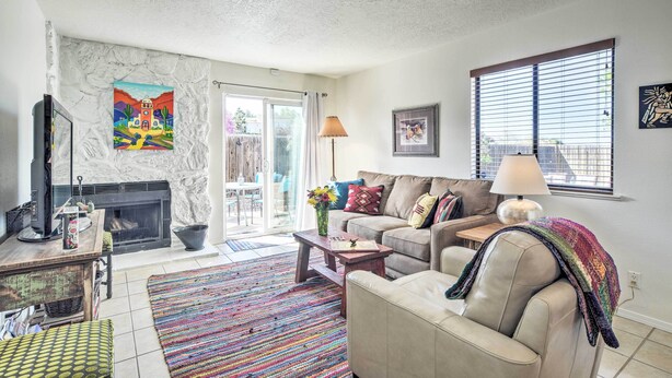 A living room with a fireplace, a sofa, a coffee table, and a colorful rug. - Mountain-view Albuquerque Townhome w/ Patio! (Albuquerque)