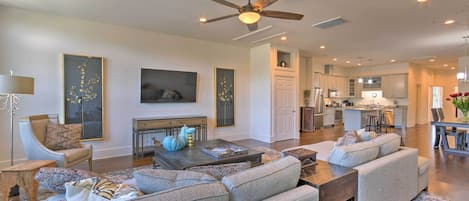 A spacious living room with a large gray sofa, a coffee table, and a ceiling fan.