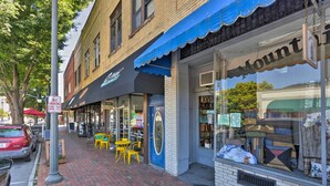 A storefront with a blue awning, a 'NO PARKING' sign, and outdoor seating with yellow chairs. - Modern Main St. Apt in Downtown Waynesville! (Waynesville)