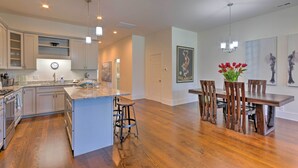 A spacious kitchen with a central island, wooden dining table, and bar stools. - Modern Main St. Apt in Downtown Waynesville! (Waynesville)