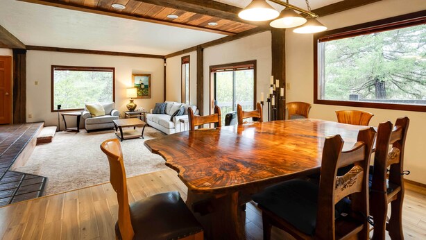 A spacious dining area with a large wooden table and chairs, a sofa, and a fireplace. - Peaceful Applegate River Valley Sanctuary! (Grants Pass)