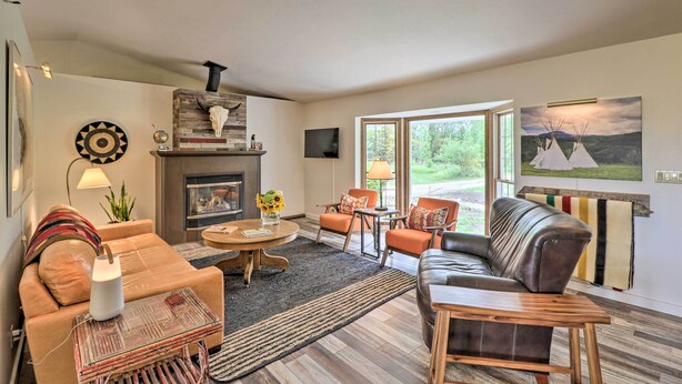 A modern living room with a fireplace, leather sofas, and a large window offering a view of the outdoors.