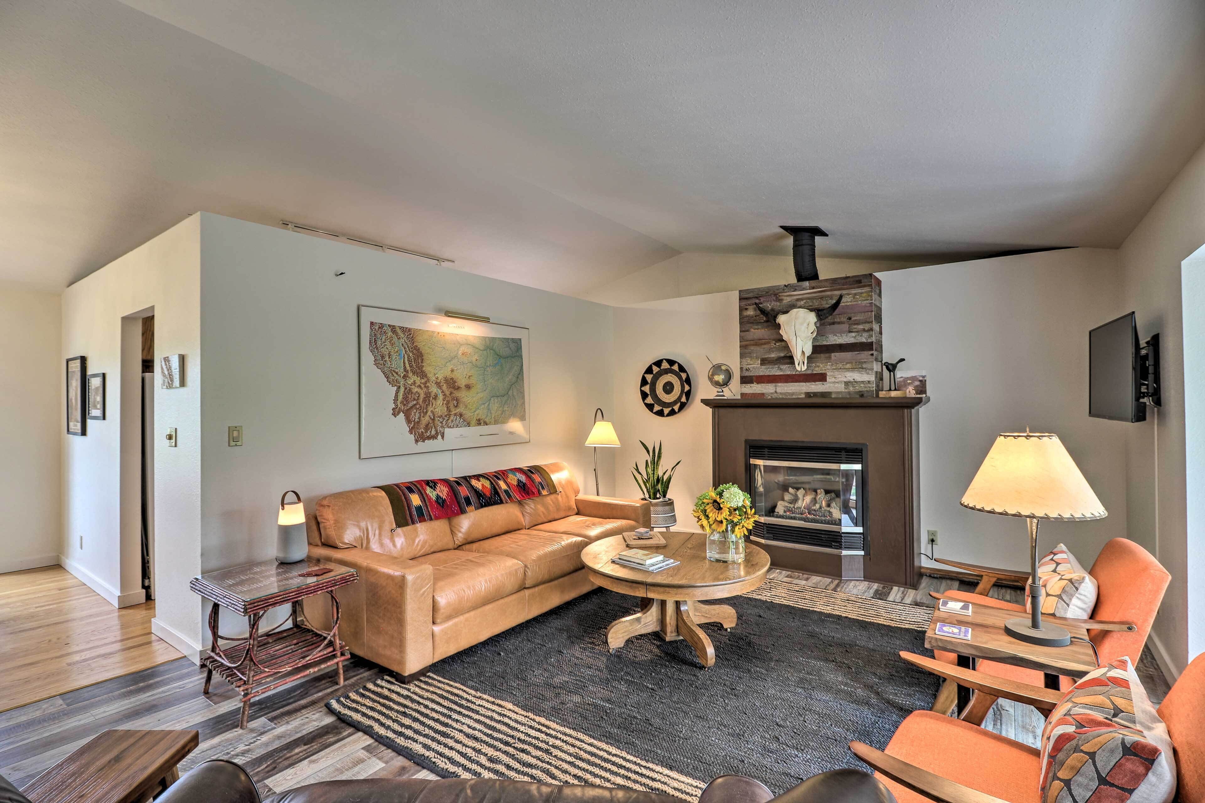 A living room with a leather sofa, a round coffee table, and a fireplace.
