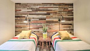 A room with two beds, a wooden wall, and a small table with a plant.