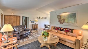 A living room with a brown leather sofa, a round coffee table with a vase of flowers, and a large map on the wall.