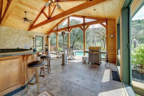 A spacious kitchen with a bar area, large windows, and a view of the outdoors. - Stunning Hopland Vacation Rental w/ Pool & Hot Tub (Hopland)