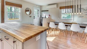 Eine moderne Küche mit Holztresen, weißen Schränken und einer Essecke mit weißen Stühlen.