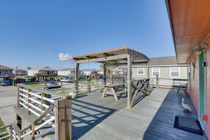 A wooden deck with a pergola, picnic tables, and a bird feeder. - Walk to Shore & Restaurants: Surfside Beach Home! (Freeport)
