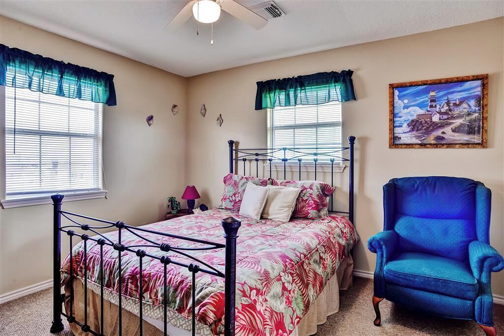 A bedroom with a bed, a chair, and a painting on the wall.
