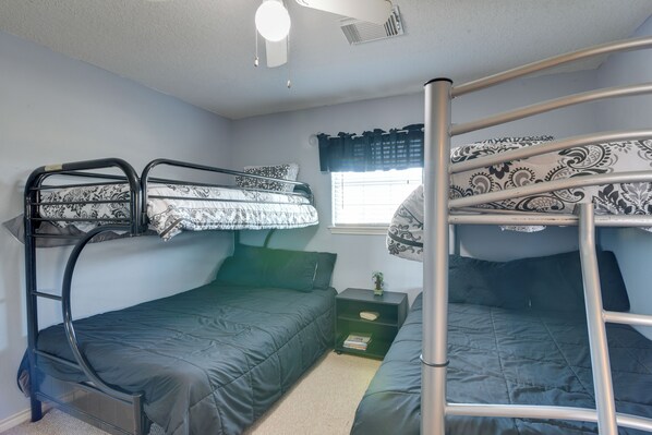A bunk bed room with a window, a small shelf, and a ceiling fan.