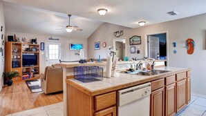 A spacious kitchen with wooden cabinets, a central island, and a built-in dishwasher. - Walk to Shore & Restaurants: Surfside Beach Home! (Freeport)