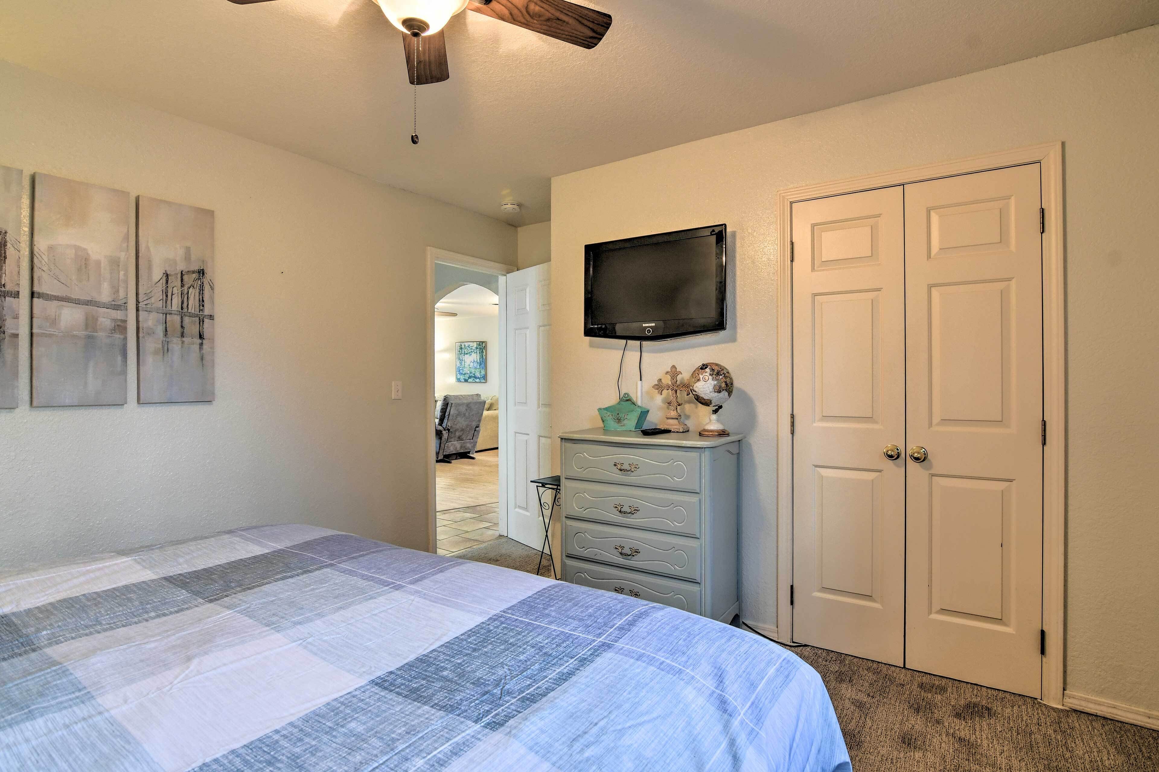 A bedroom with a bed, a dresser, a television, and a door.