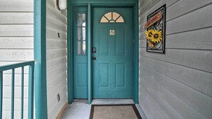 A teal door with a welcome sign and a sunflower decoration.