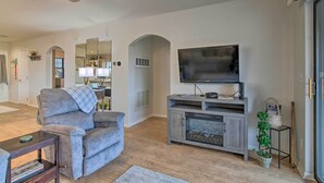 A living room with a gray sofa, a fireplace, a TV, and a ceiling fan.