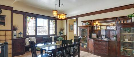 Comedor con mesa y sillas de madera, una lámpara de araña y un ventanal de vitrales.