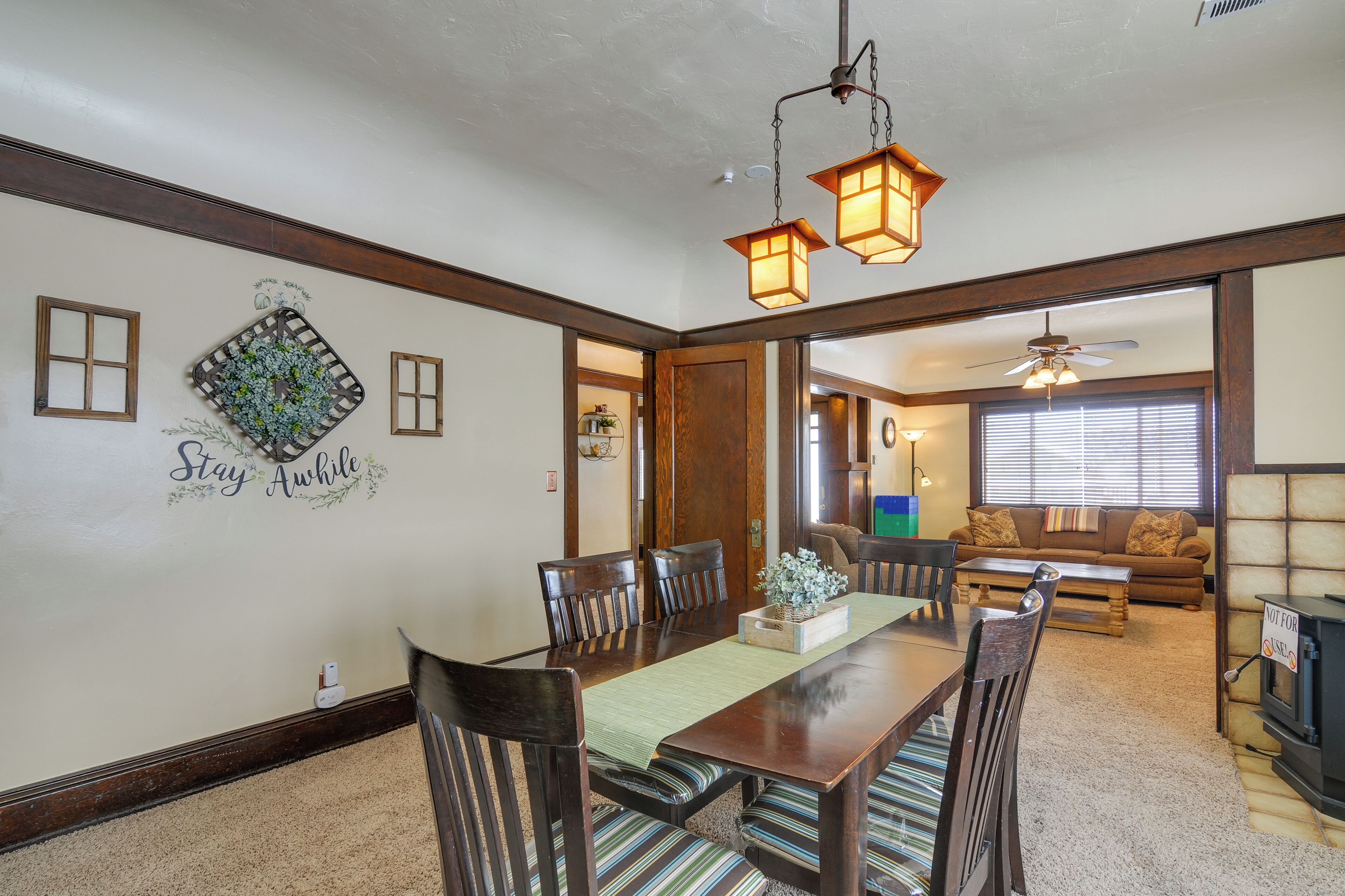 A dining area with a wooden table, chairs, and a decorative wall with a 'Stay Awake' sign.
