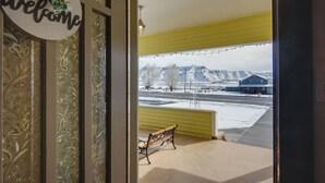 A view from inside a building looking out to a snowy landscape with a bench and a 'welcome' sign. - Beautiful Historic Home Near Bryce Canyon! (Cannonville)