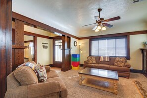 A living room with a wooden ceiling, a ceiling fan, a brown sofa, a coffee table, and a window with blinds.