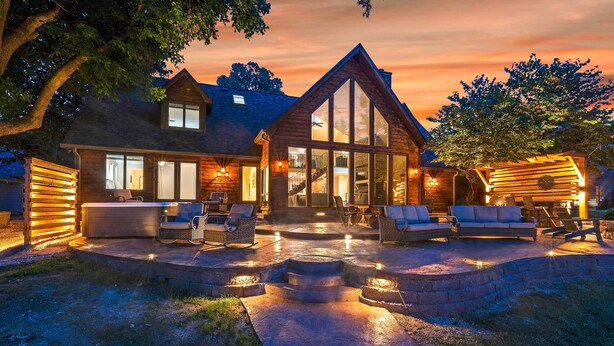 A large, two-story log cabin with a spacious patio area featuring outdoor seating and a fire pit. - Spacious Lakefront Home w/ Private Dock! (Hollister)