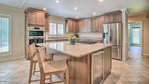A modern kitchen with a central island, stainless steel appliances, and wooden cabinetry. - Spacious Lakefront Home w/ Private Dock! (Hollister)