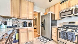 A kitchen with wooden cabinets, a stainless steel refrigerator, a microwave, and a stove. - Detroit Home w/ Pool & Yard, 15 Mi to Downtown! (Redford)
