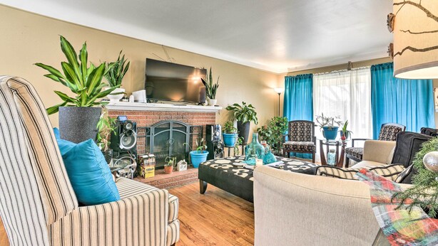 A living room with a fireplace, multiple chairs, sofas, and potted plants. - Detroit Home w/ Pool & Yard, 15 Mi to Downtown! (Redford)