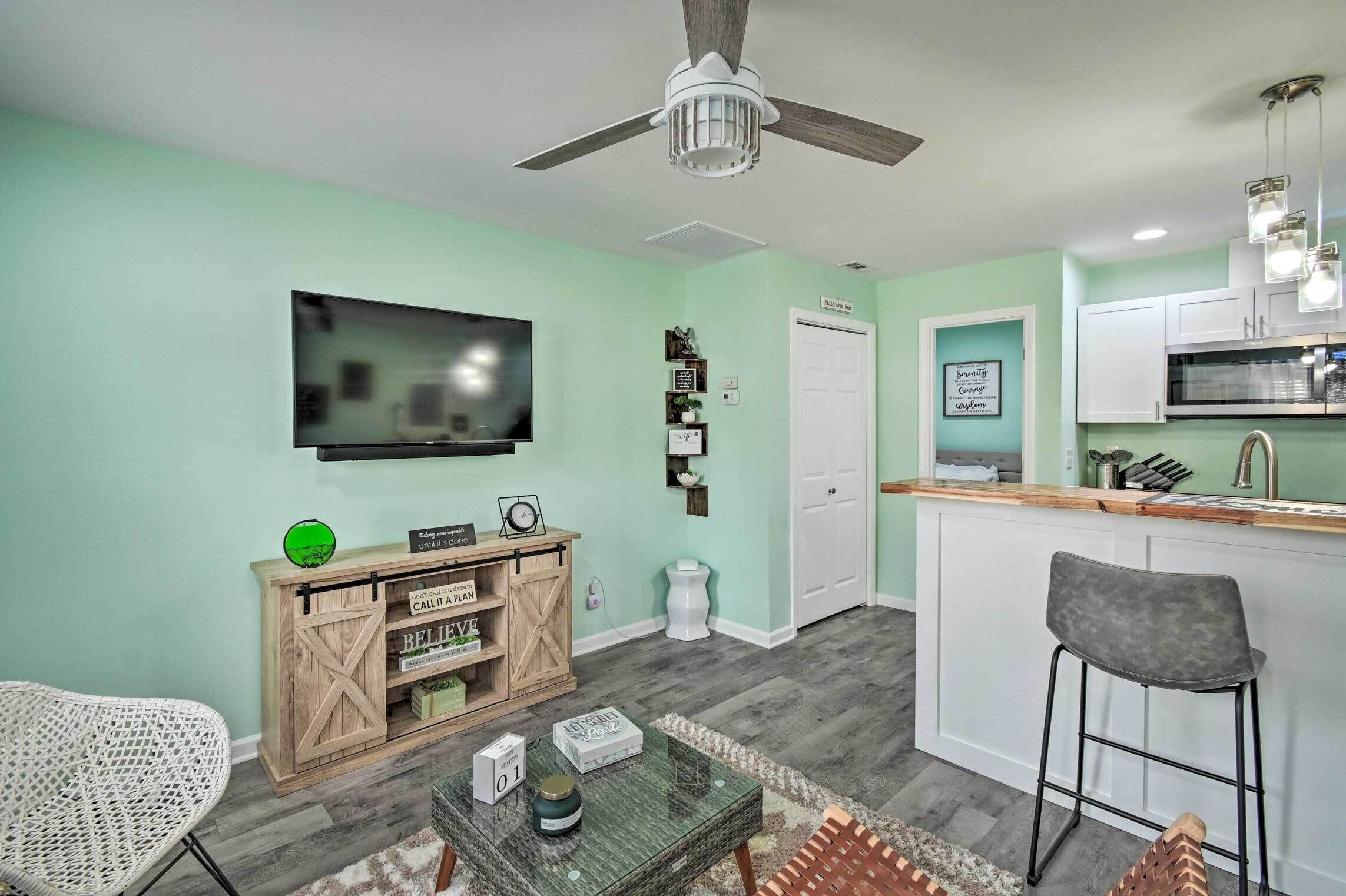 A modern kitchen with a bar area, a dining table, and a television.