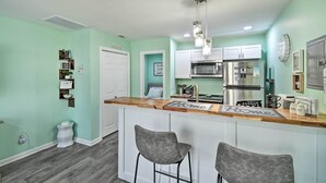 A kitchen with a bar area, white cabinets, stainless steel appliances, and a light green wall. - Pet-friendly Fayetteville Vacation Rental! (Fayetteville)