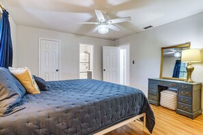 A bedroom with a bed, a dresser, a mirror, and a ceiling fan.