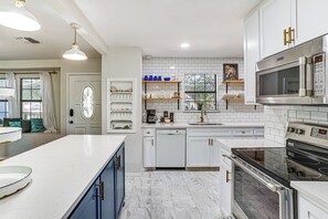 A modern kitchen with white cabinetry, a Bosch dishwasher, a Maytag microwave, and a black stove.
